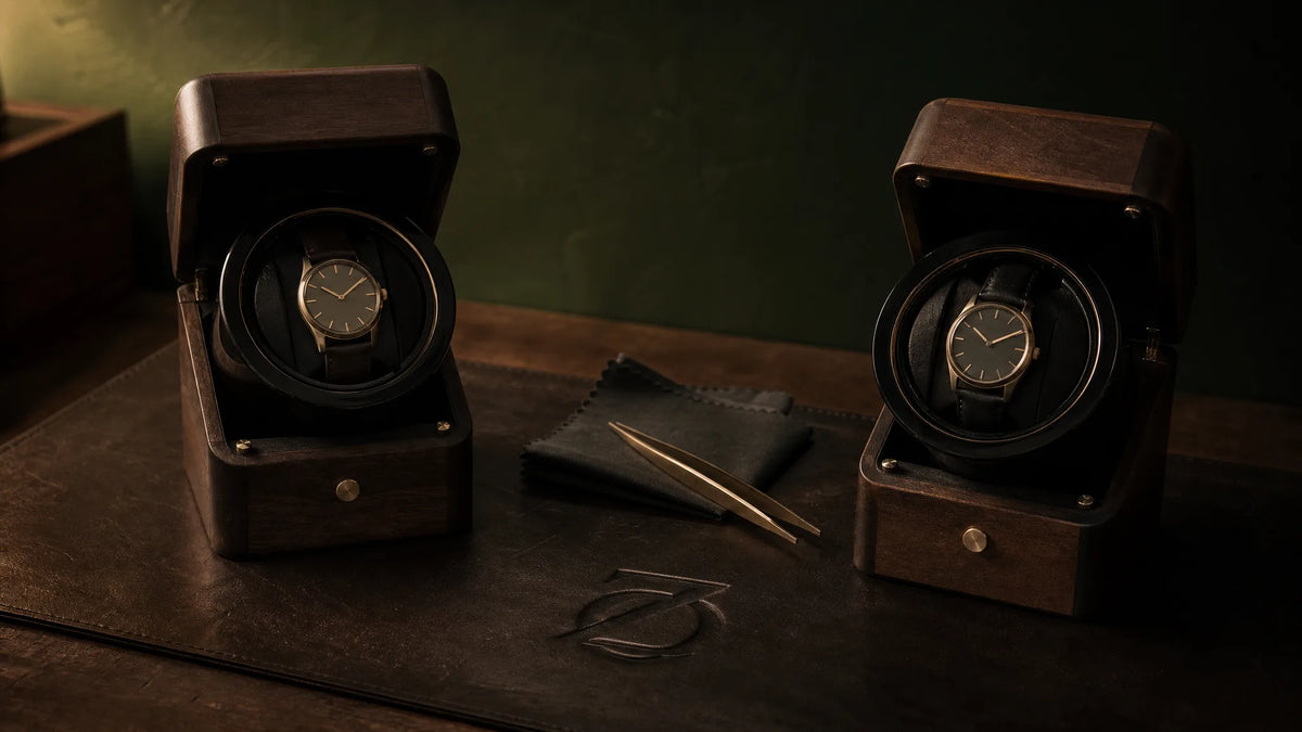 Two watch winders running side by side on the test bench, tweezers and a cloth between them